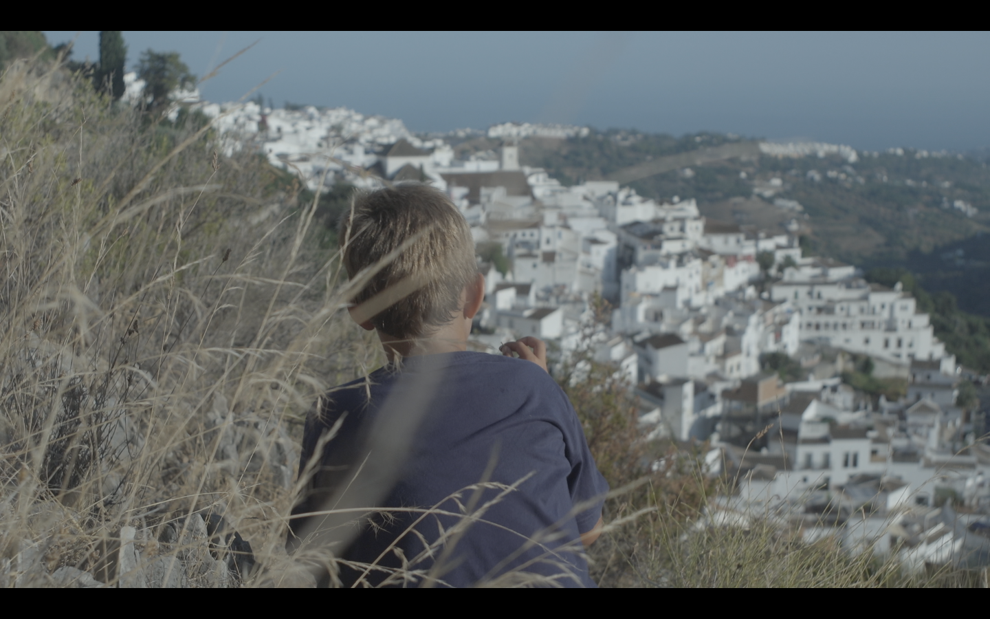 Oliver zittend boven dorp op berg